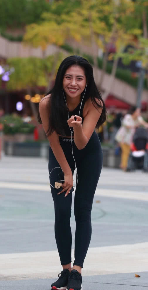 时尚小姐姐穿着紧身裤搭配抹胸装，在广场上玩街拍，搞怪的姿势很