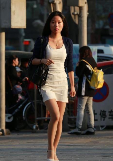  「一字」街拍：小姐姐身穿黑色的一字肩上衣，搭条黑色的短裤，显得时尚又洋气