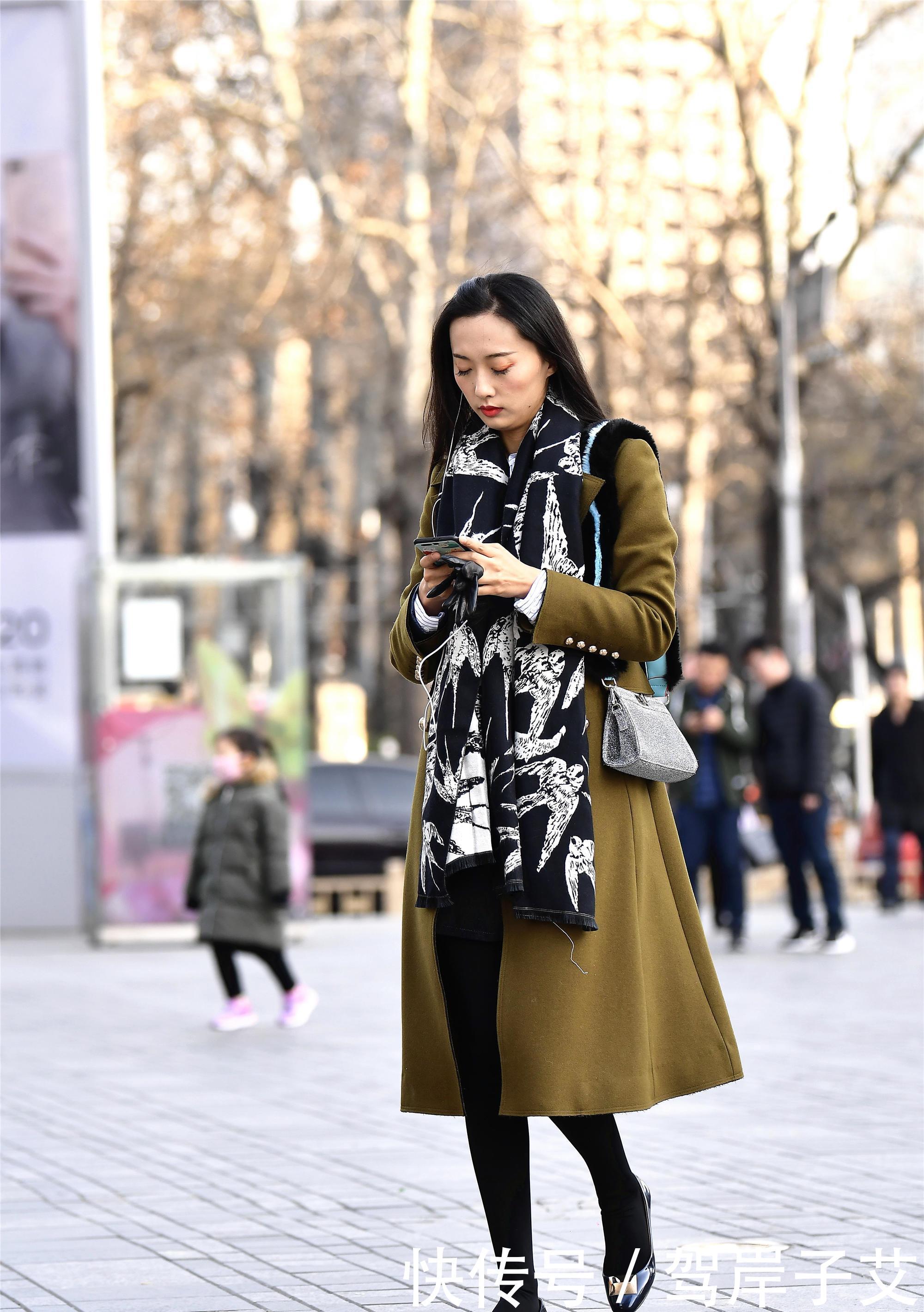 美女■街拍:美女搭配黄绿色的风衣,一条黑色打底裤,身材高挑美丽时尚