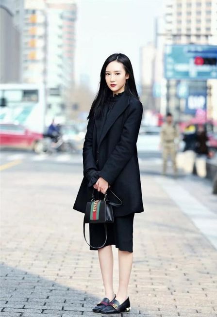 小美女:街拍:小美女身穿黑色套装,手里拿着包包,笑容甜美