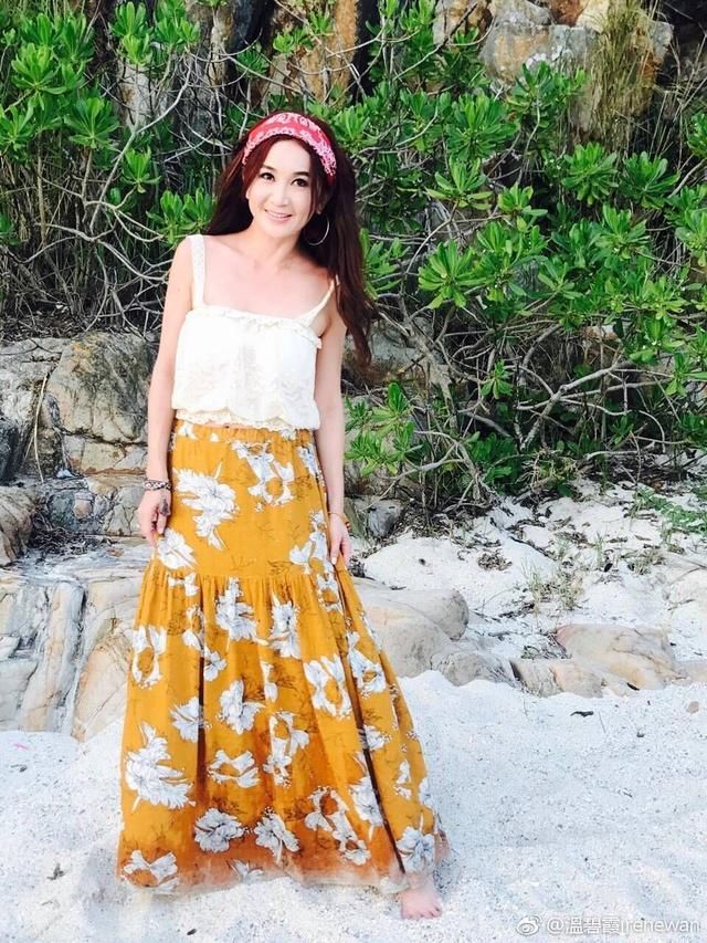 52岁温碧霞清新黄裙海边戏水，在一旁的老公却像“果园老农”!