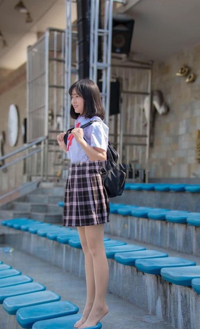 穿着校服的小姐姐坐在球场看台上,露出肉色丝袜包裹的小脚丫