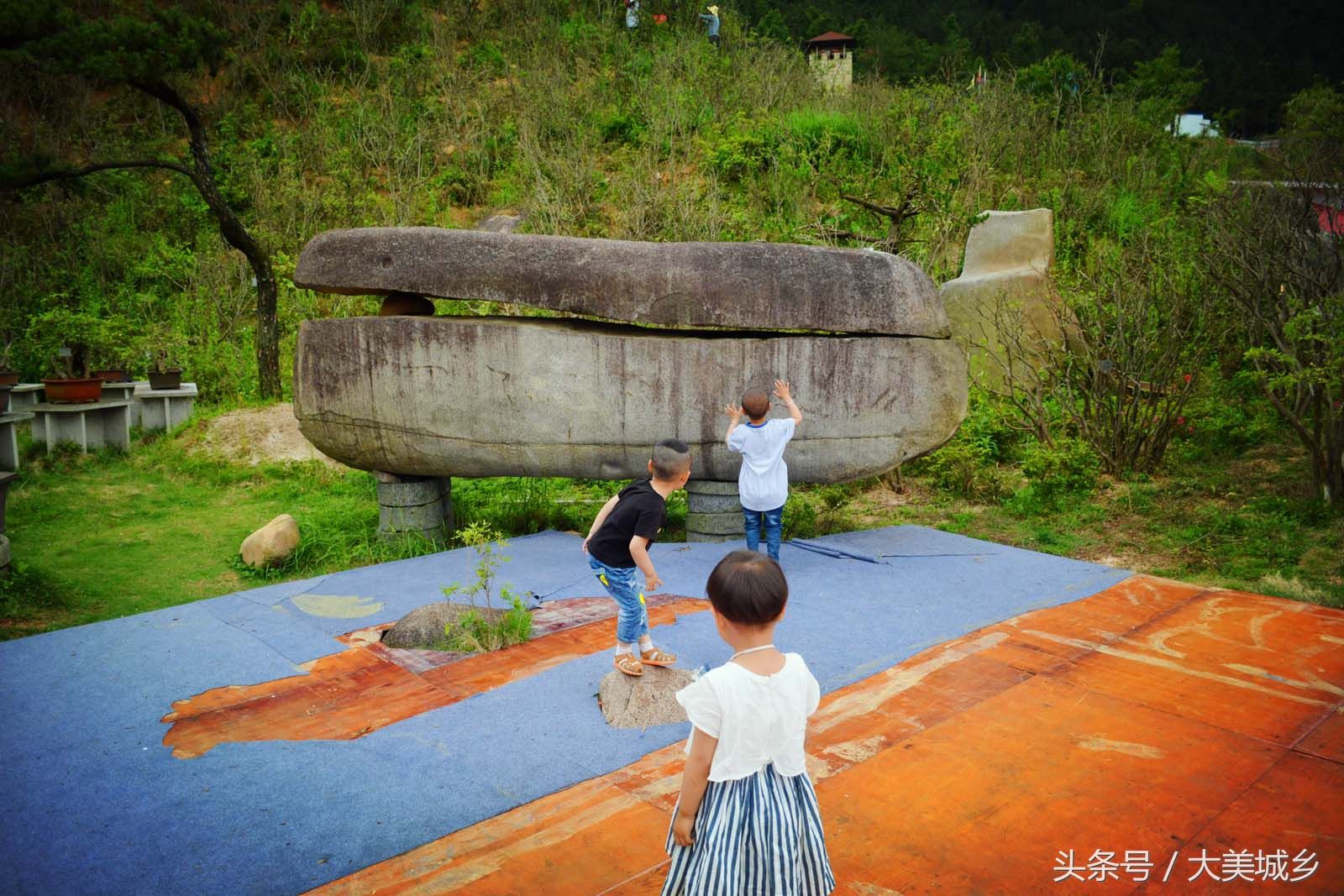 景区放置巨大“石棺”寓意升官发财 孩童在下面玩捉迷藏