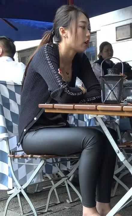 街拍:穿紧身黑皮裤绑马尾辫坐着的性感美女