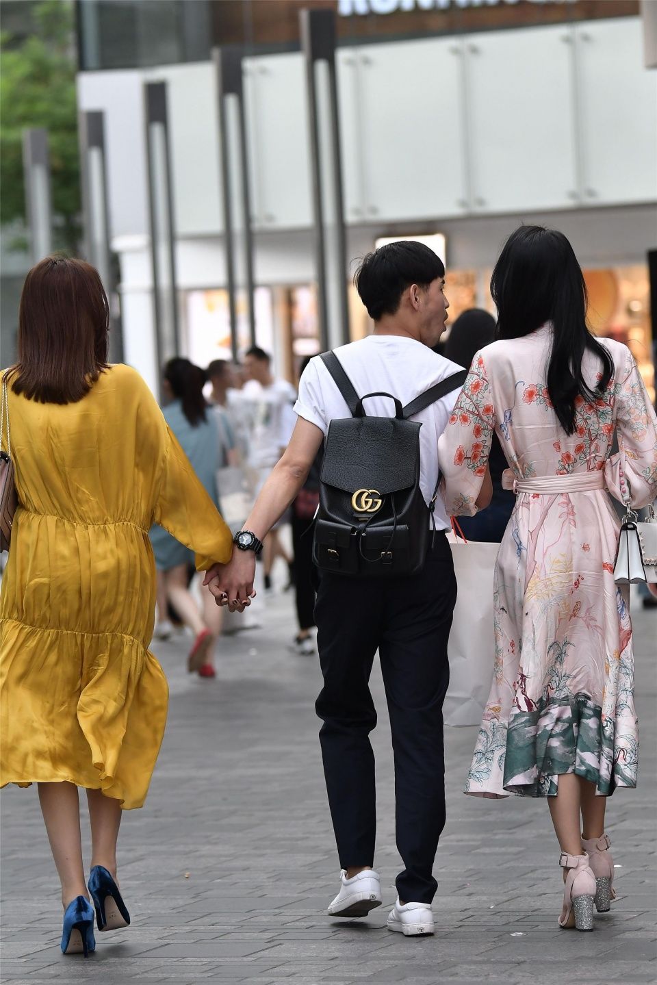 小伙子带着两位时尚长裙的姑娘，哪一位是他的女友呢?