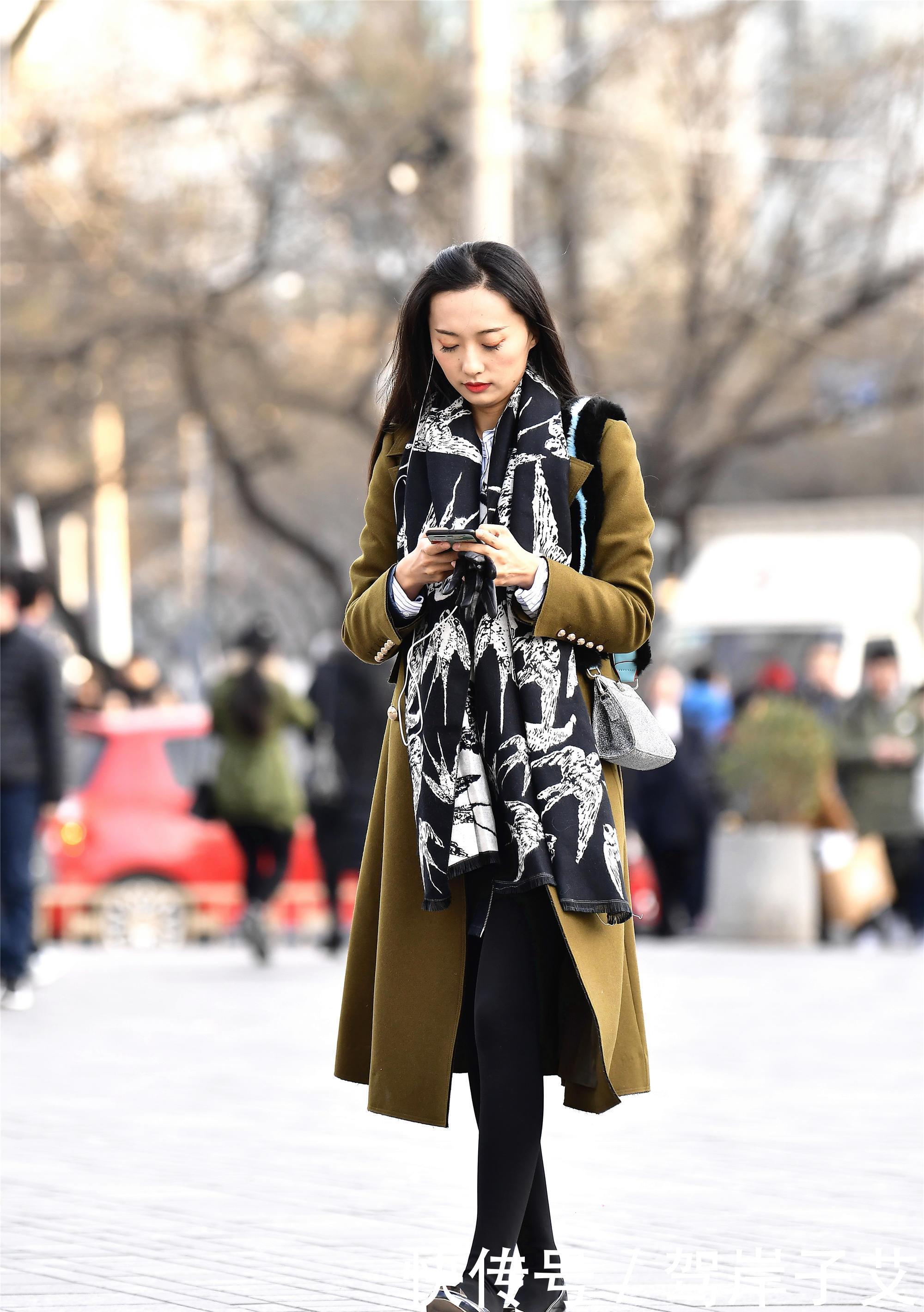 美女■街拍:美女搭配黄绿色的风衣,一条黑色打底裤,身材高挑美丽时尚