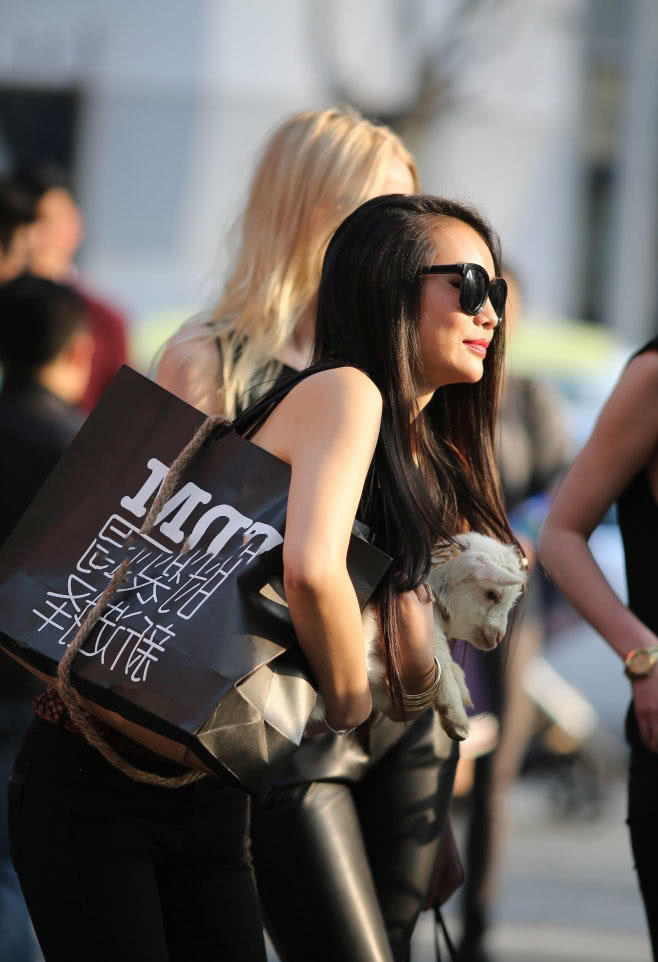 怀抱小羊的小姐姐牛仔裤搭配黑色小背心，有爱心的女人很美