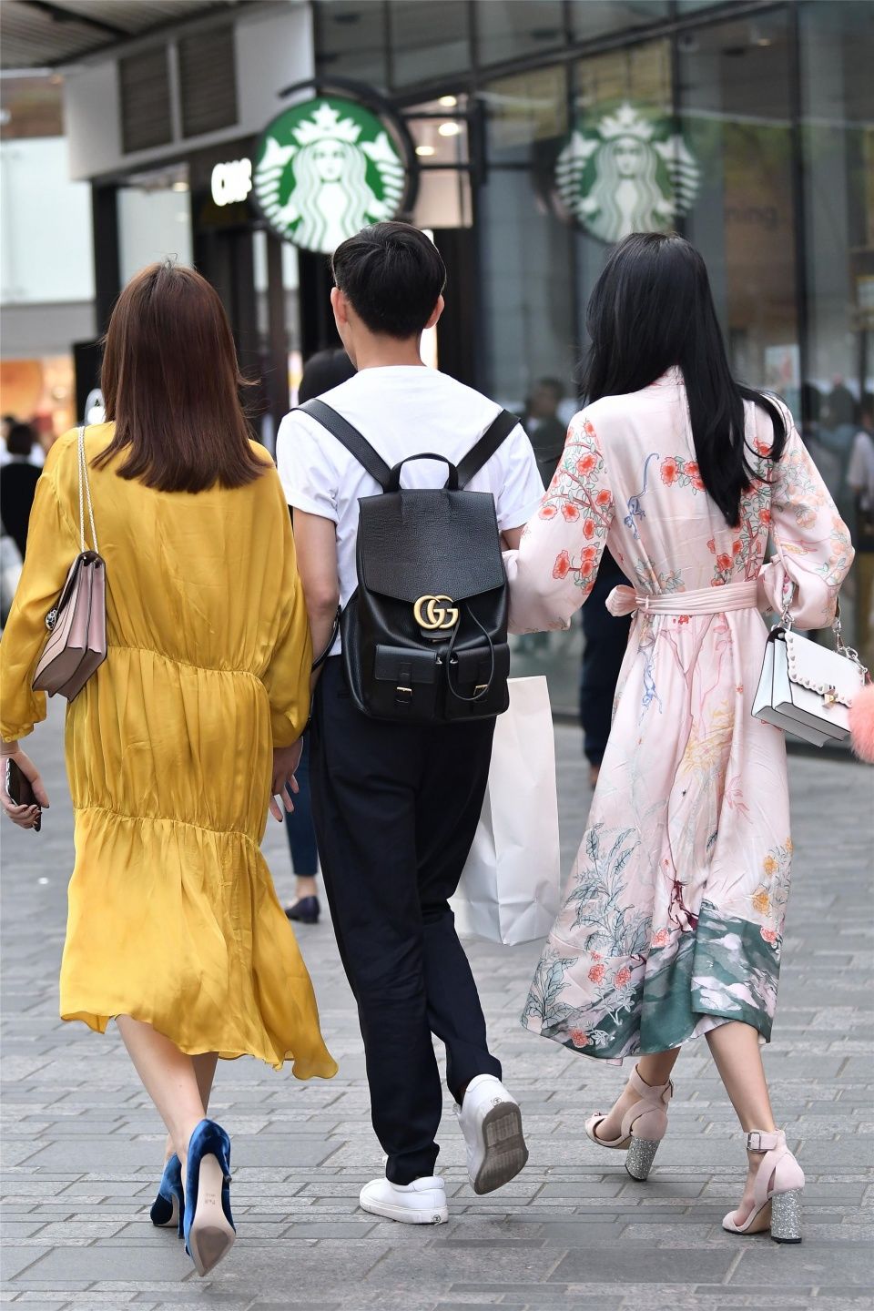 小伙子带着两位时尚长裙的姑娘，哪一位是他的女友呢?