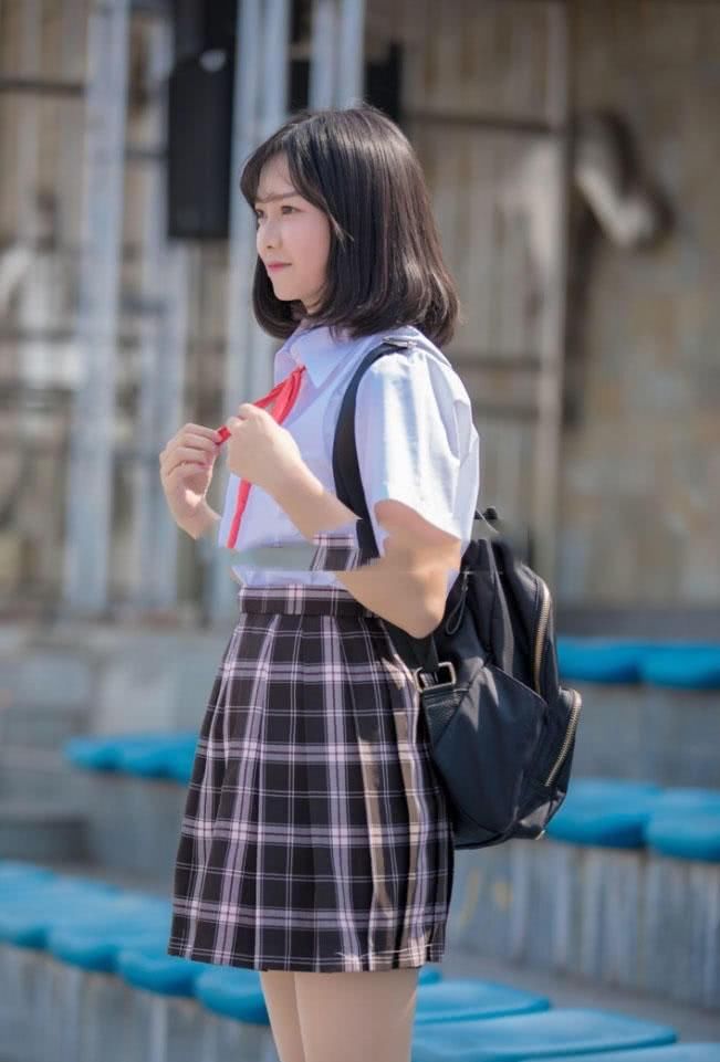 穿着校服的小姐姐坐在球场看台上，露出肉色丝袜包裹的小脚丫