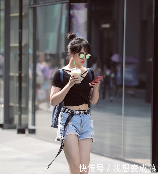 路人街拍，皮肤白皙的美女穿露脐装配紧身牛仔裤，身材妩媚而性感