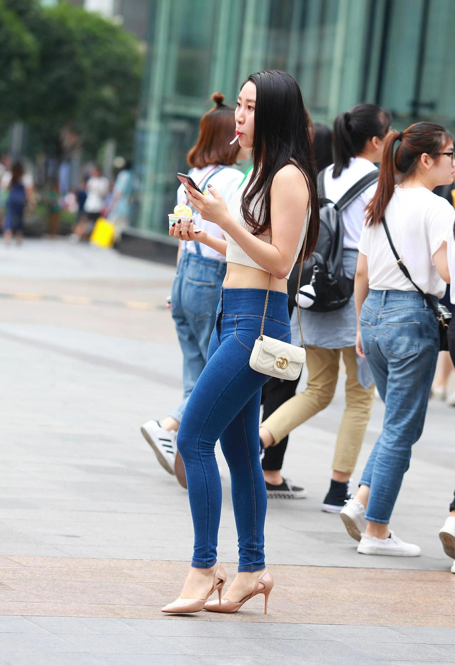 气质小姐姐紧身牛仔裤搭配大气十足，嘴里含着小勺子尽显可爱呆萌