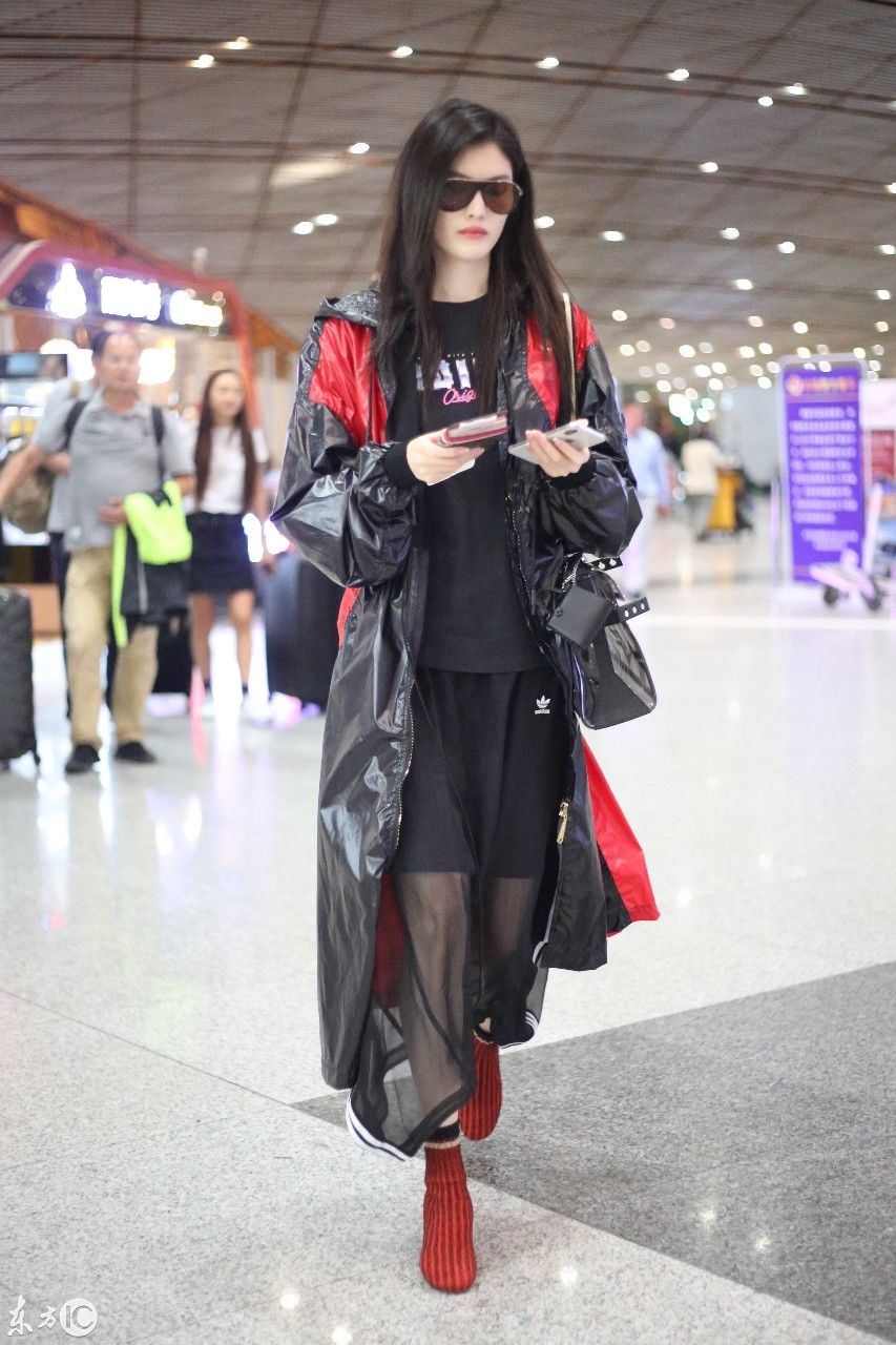 超模何穗现身北京机场，一身雨衣，难掩美腿