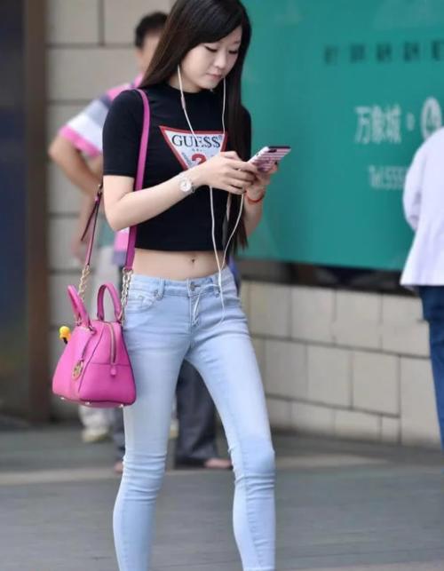 小姐姐上身搭配了一件灰色的紧身运动背心，露脐装搭配紧身牛仔裤