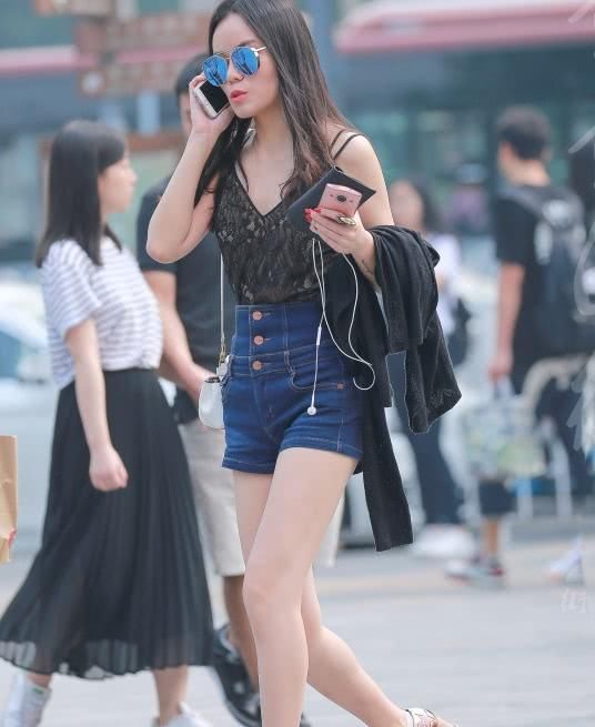 墨镜姐姐紧身牛仔短裤穿出修长大美腿，打电话的表情有些羞涩