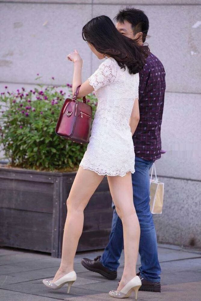 走在街上的小姐姐身穿白色连衣裙,展示出别致的美感