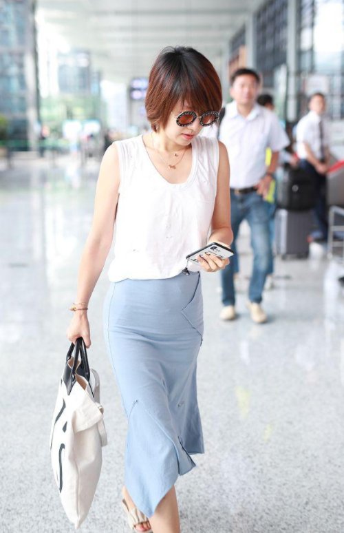 马伊琍赶飞机踩脱鞋身，穿无袖白色背心搭配半身裙清爽怡人