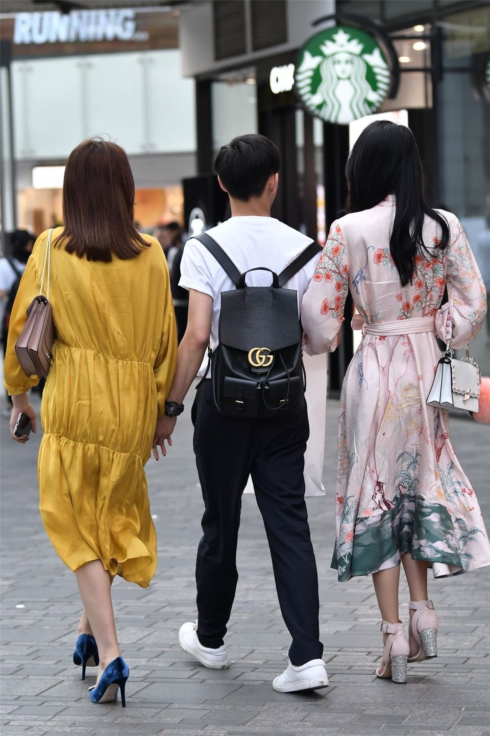 小伙子带着两位时尚长裙的姑娘，哪一位是他的女友呢?