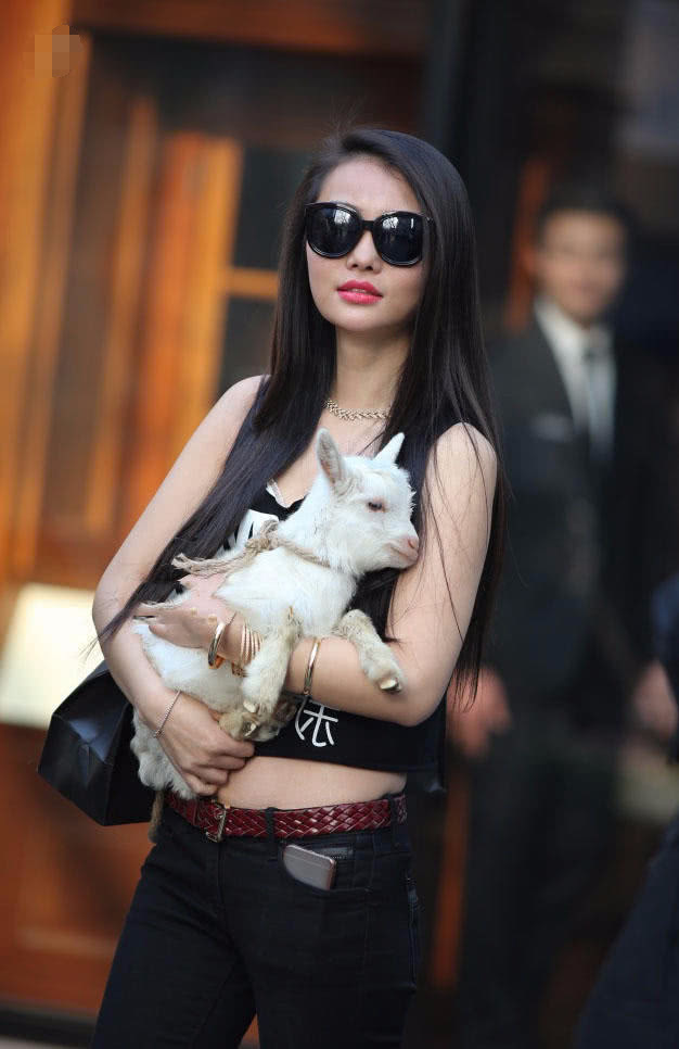 怀抱小羊的小姐姐牛仔裤搭配黑色小背心，有爱心的女人很美