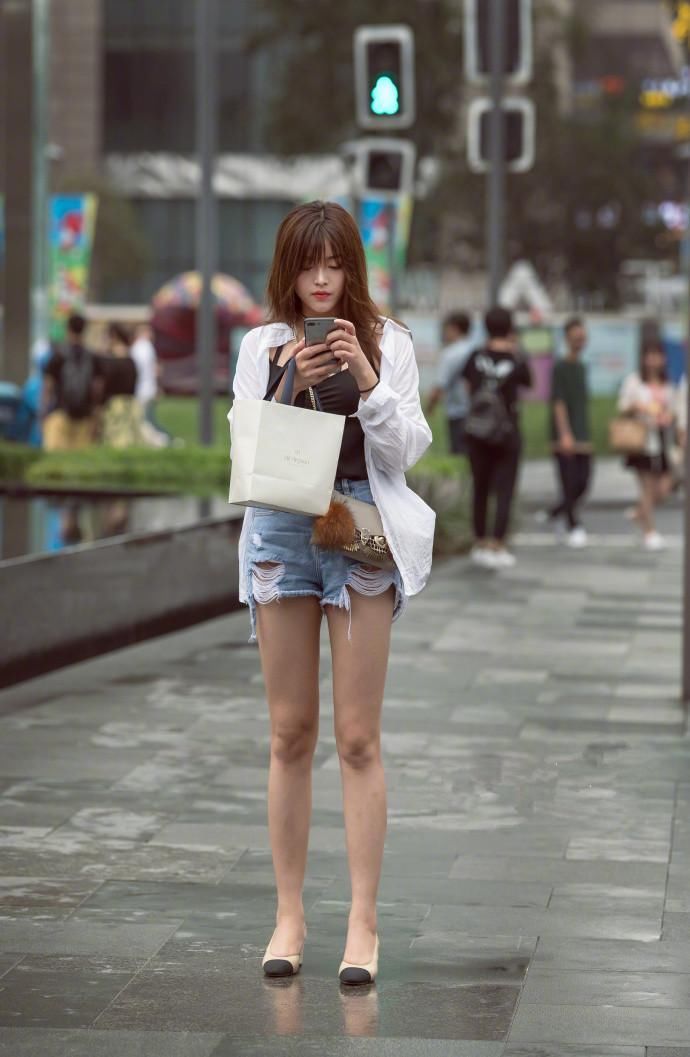 街拍:大波浪卷的小姐姐专心玩手机，双腿笔直又修长，太美了!
