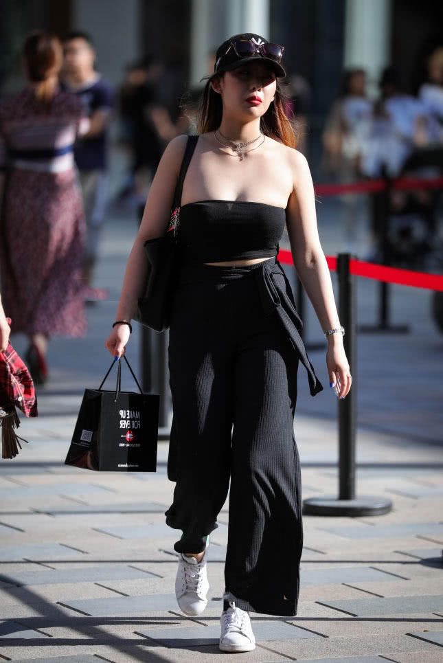 小姐姐头戴黑色鸭舌帽，上身是一件黑色的抹胸装