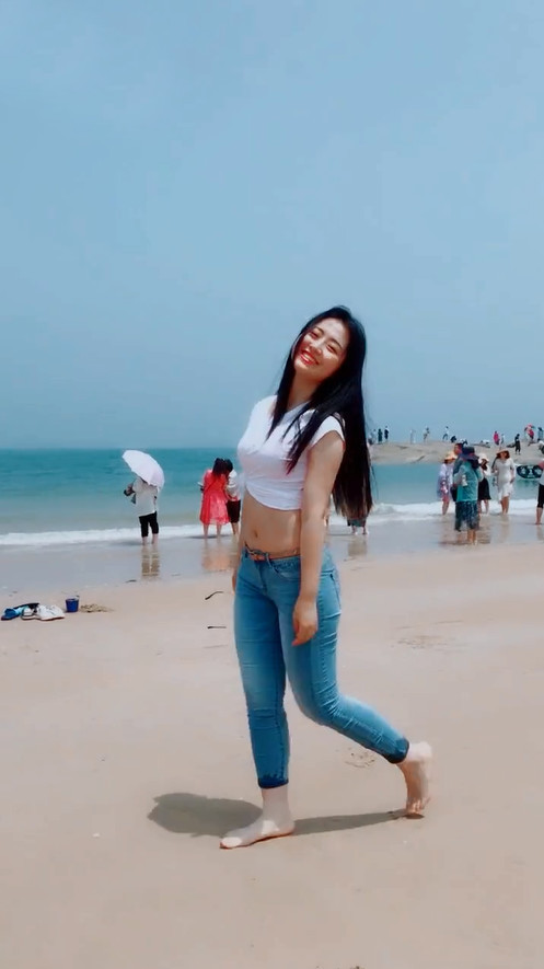 牛仔裤妹子穿高跟鞋太久了，索性光脚与沙滩来一次亲密接触