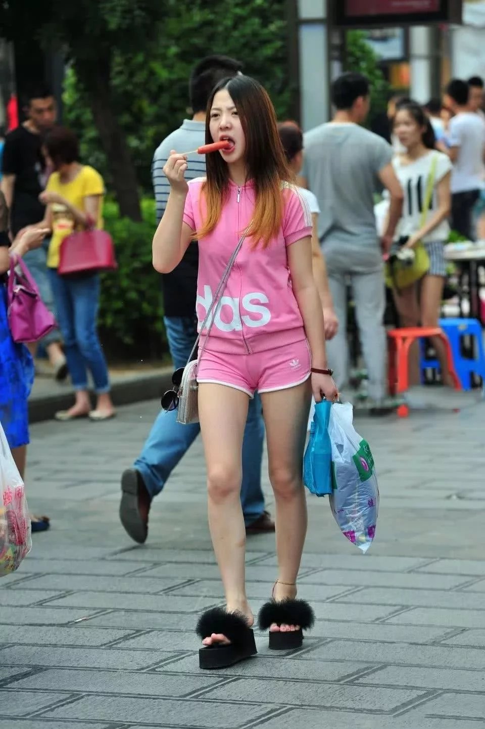 运动装的小姐姐尽显凹凸有致的身材，走路吃热狗吸睛无数