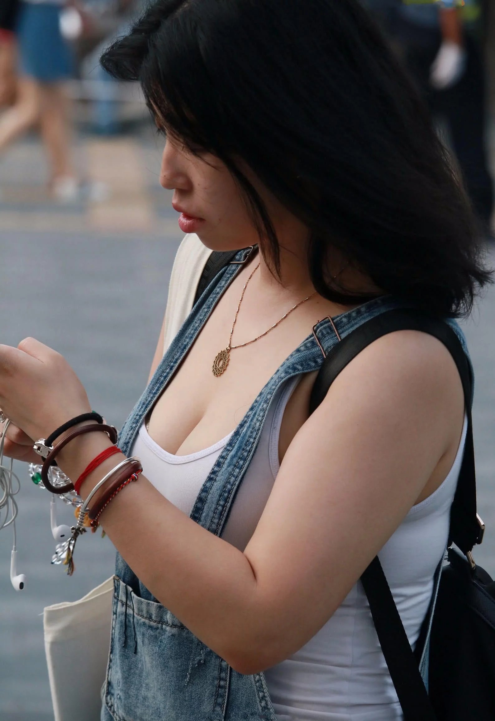 只顾低头玩手机的妙龄少妇，背心下包裹着傲人的玲珑身材，走在大