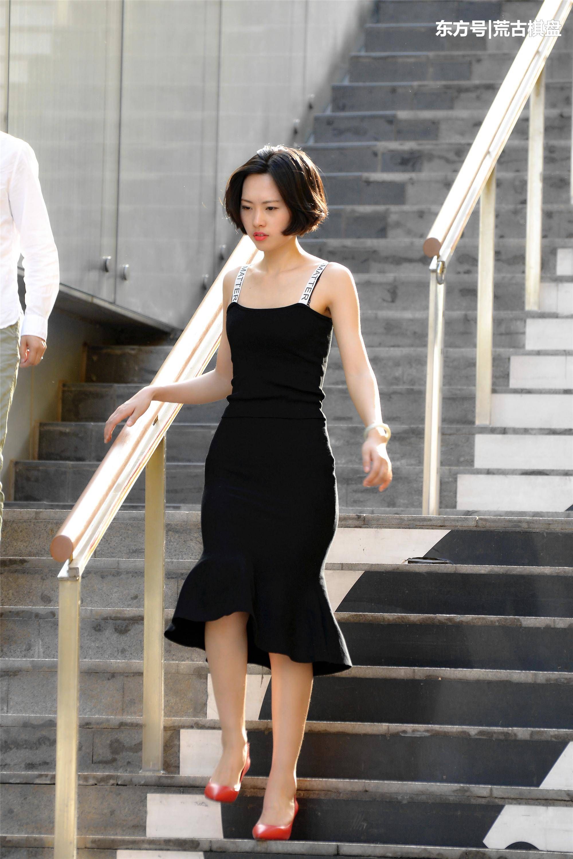黑色吊带长裙姑娘穿着尖头细高跟在台阶上走上走下，忙碌着什么?