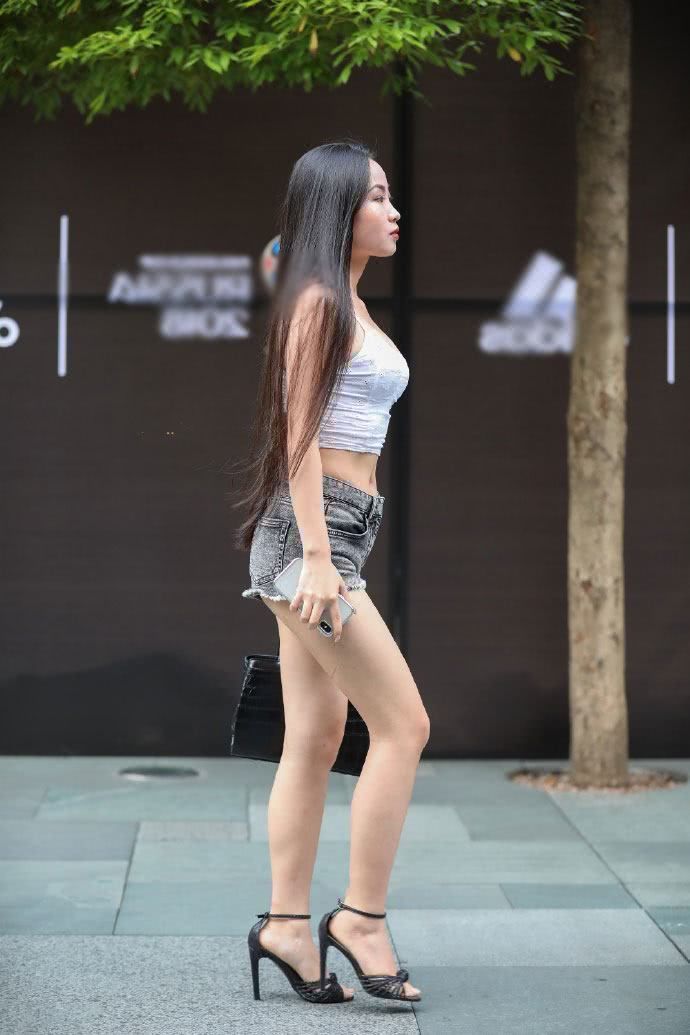 路人街拍，吊带装搭配时尚热裤，露出一双白皙的美腿，个性张扬