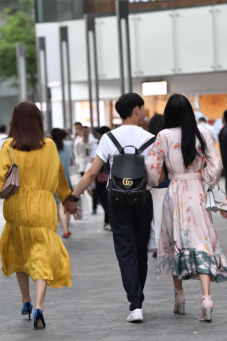 小伙子带着两位时尚长裙的姑娘,哪一位是他的女友呢?