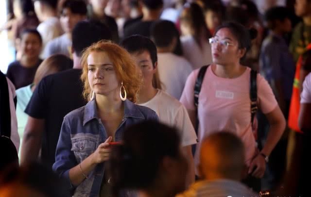 外国游客扎堆逛小吃街,小伙忙着吃串,美女专挑人多的地方留影