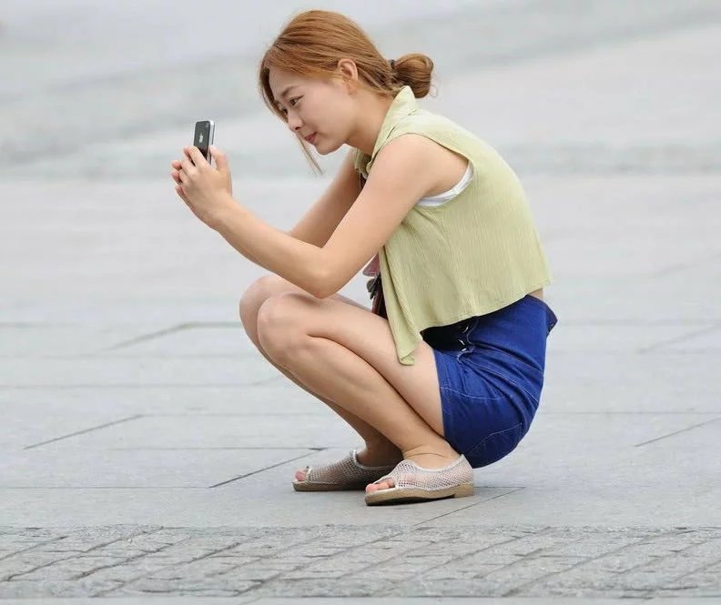 小姐姐高腰小热裤搭配白色小背心显曼妙身姿，自拍时的样子真的好