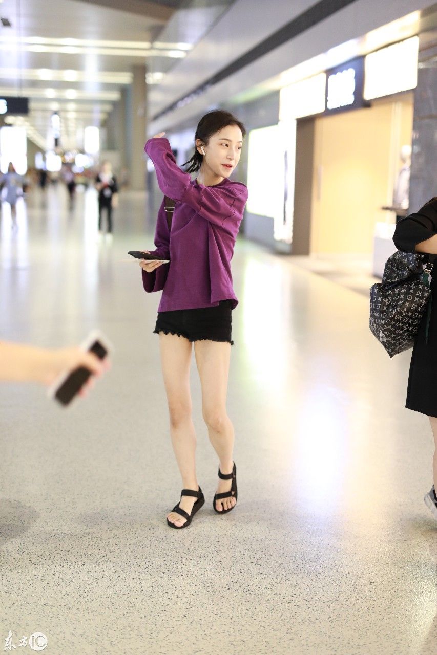 姜梓新穿紫色卫衣搭配黑短裤现身机场，皮肤白皙面带微笑大秀美腿