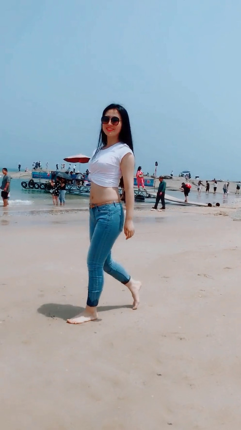 牛仔裤妹子穿高跟鞋太久了，索性光脚与沙滩来一次亲密接触