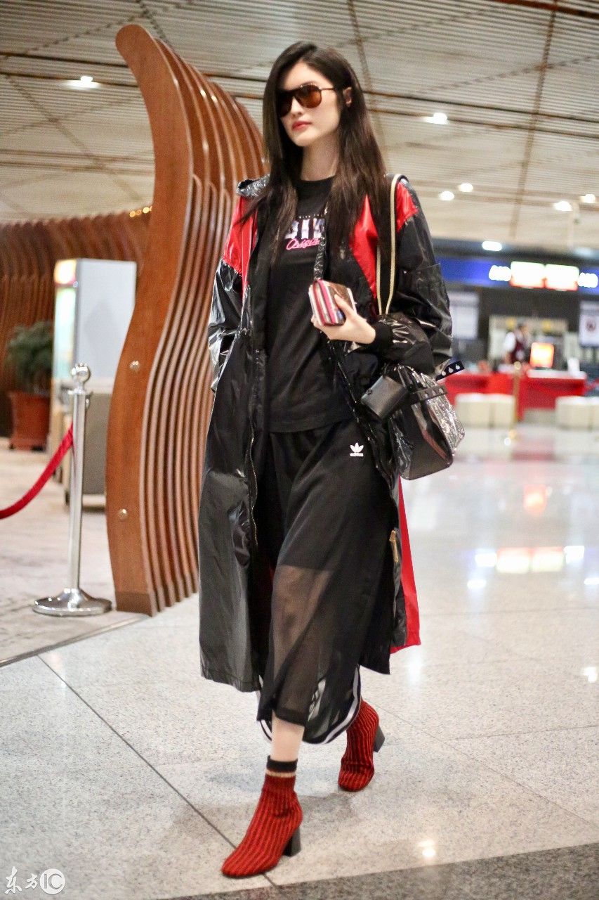 超模何穗现身北京机场，一身雨衣，难掩美腿