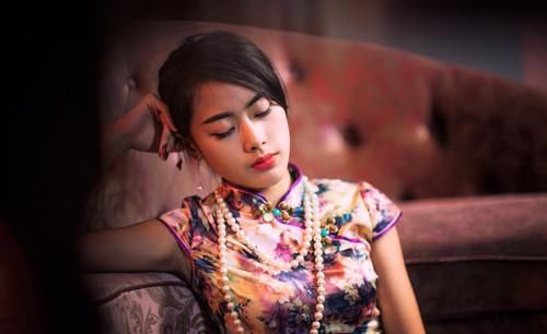 一位身穿旗袍的古典美女，慵懒的坐在沙发上美艳动人