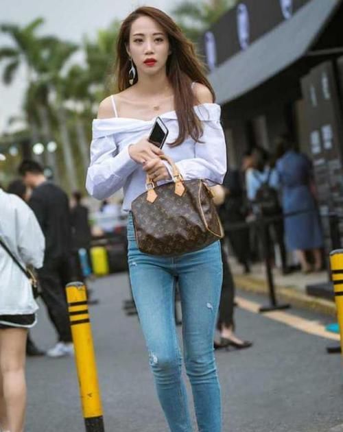  『蓝色』美女时尚街拍：身材高挑的美女，一件白色一字肩配蓝色牛仔裤，都市丽人范