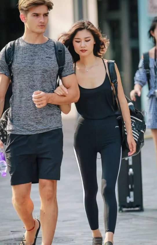 气质小姐姐身穿紧身裤跟男朋友出门，宽松的吊带大低领的设计把小