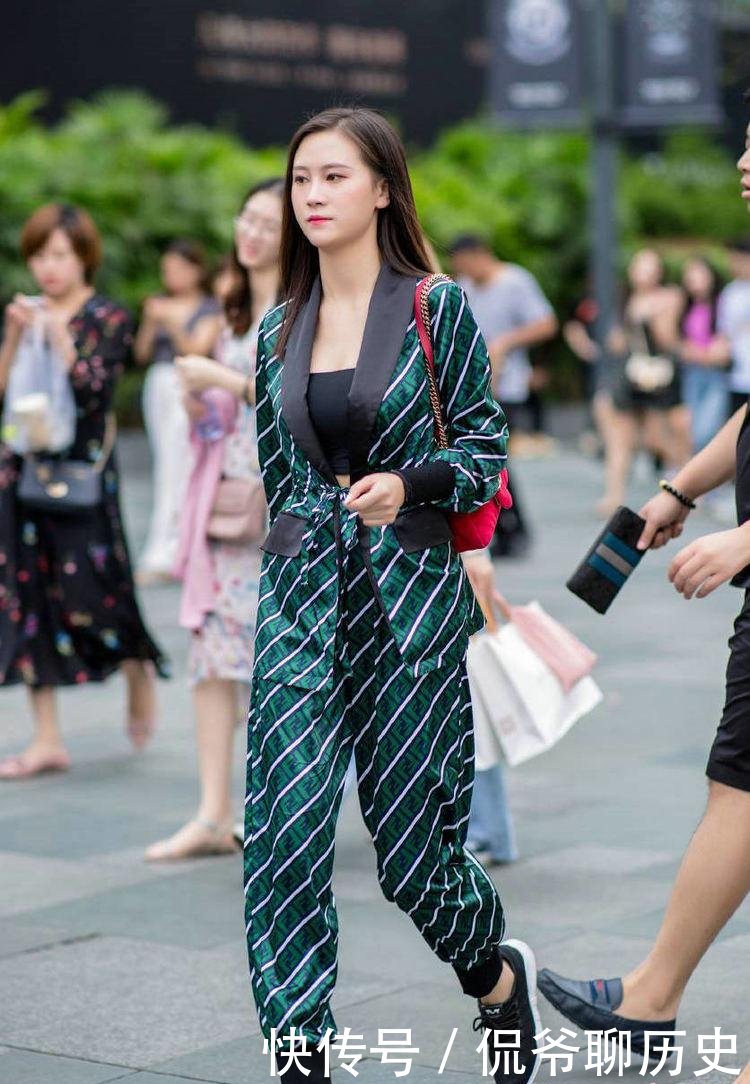  『显得』小姐姐身穿绿色条纹套装，搭配一双黑色运动鞋，显得特别精神