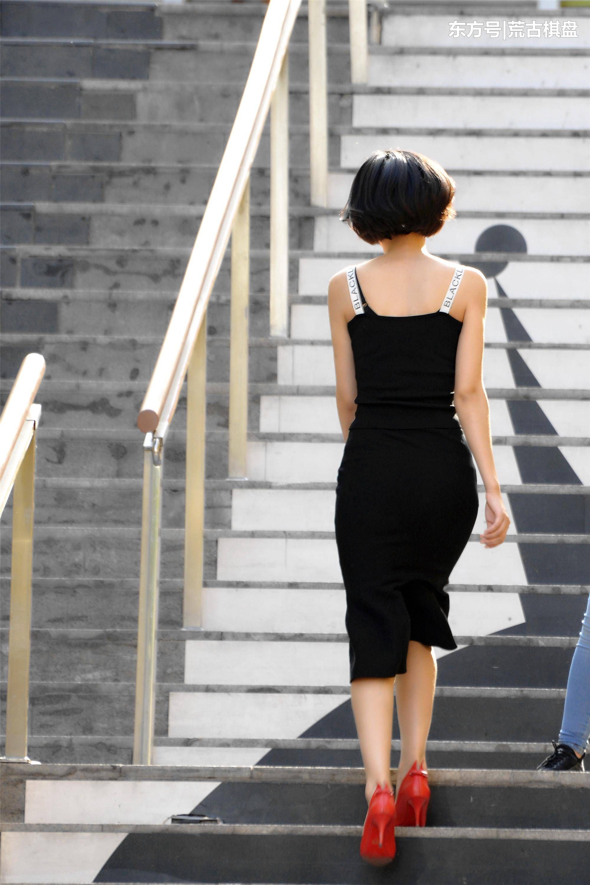 黑色吊带长裙姑娘穿着尖头细高跟在台阶上走上走下，忙碌着什么?
