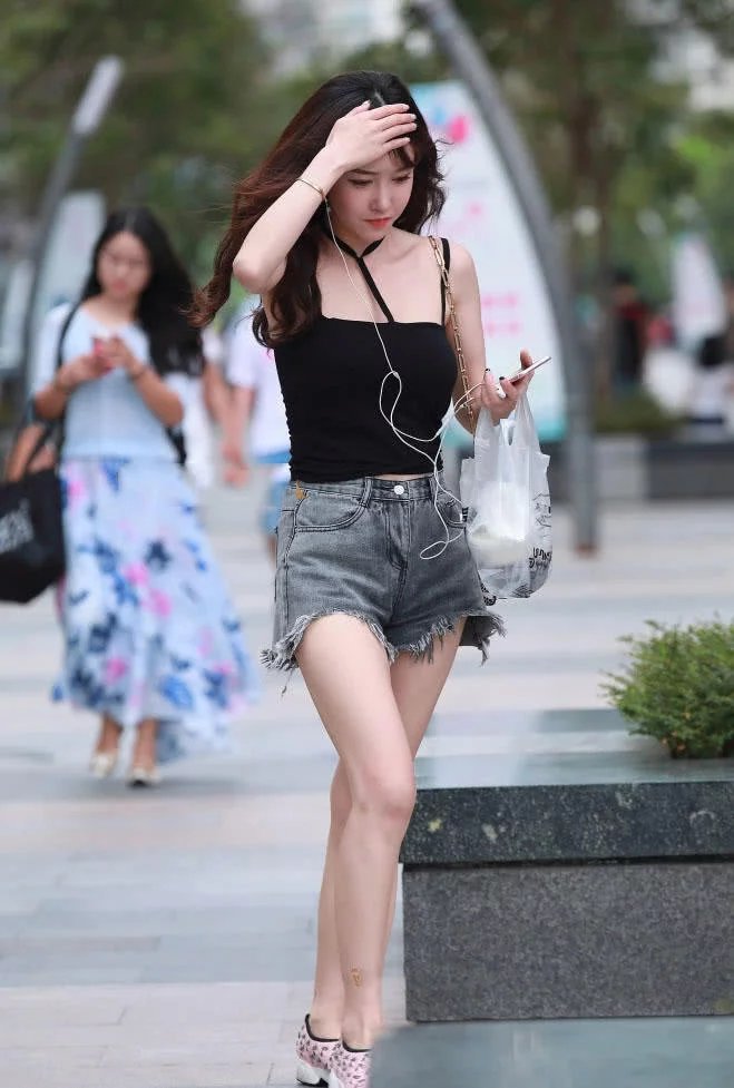 娇美小姐姐吊带背心搭配热裤显出曼妙身材，轻抚头发的样子好迷人