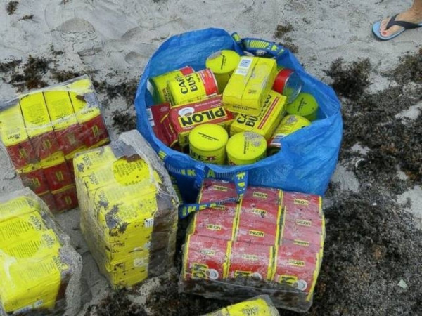 男子在沙滩游玩，海里冲上来许多黄色罐子，引来附近居民疯狂捡拾