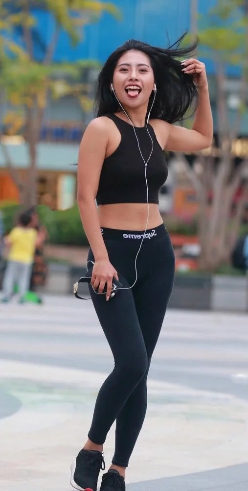 时尚小姐姐穿着紧身裤搭配抹胸装，在广场上玩街拍，搞怪的姿势很