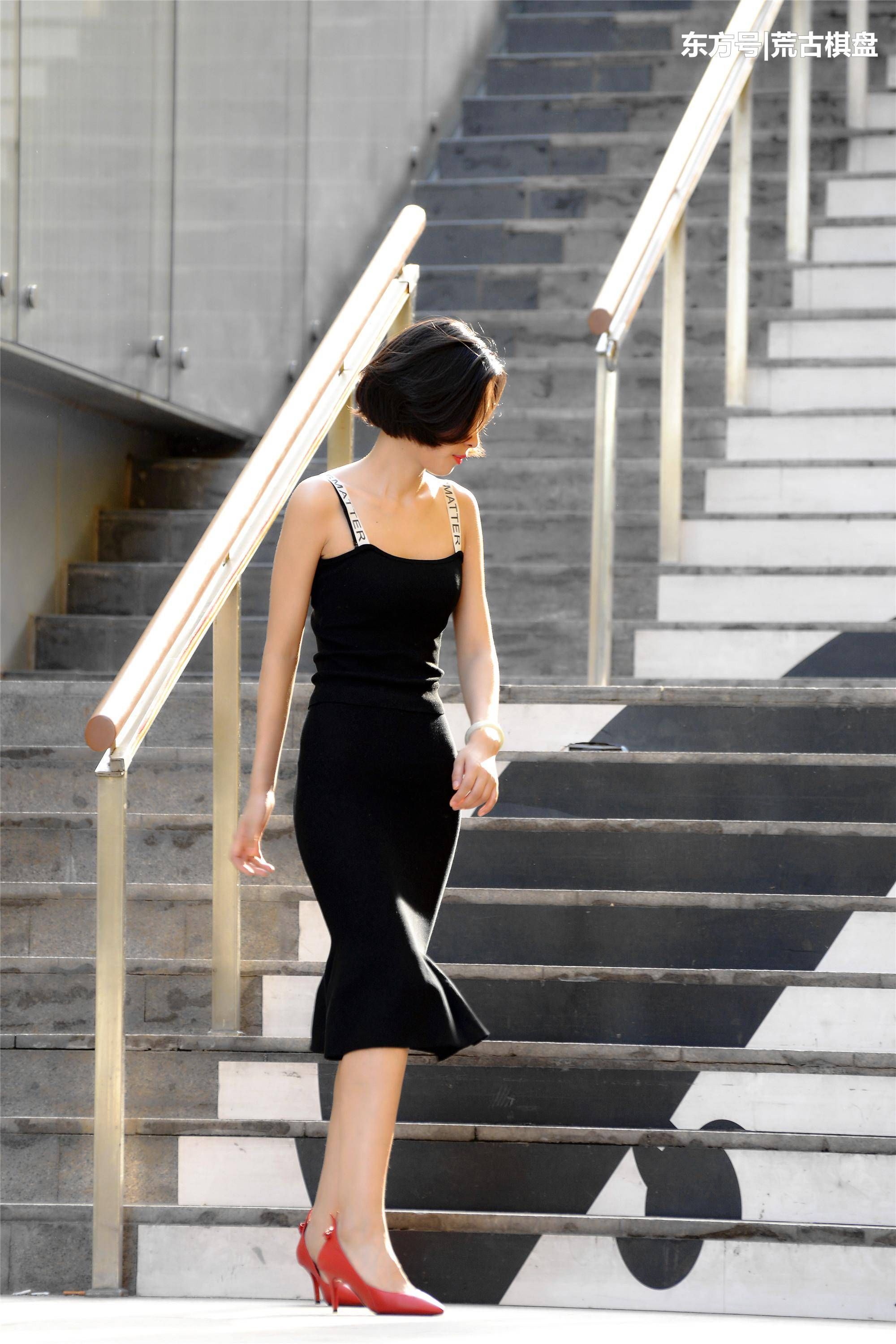 黑色吊带长裙姑娘穿着尖头细高跟在台阶上走上走下，忙碌着什么?