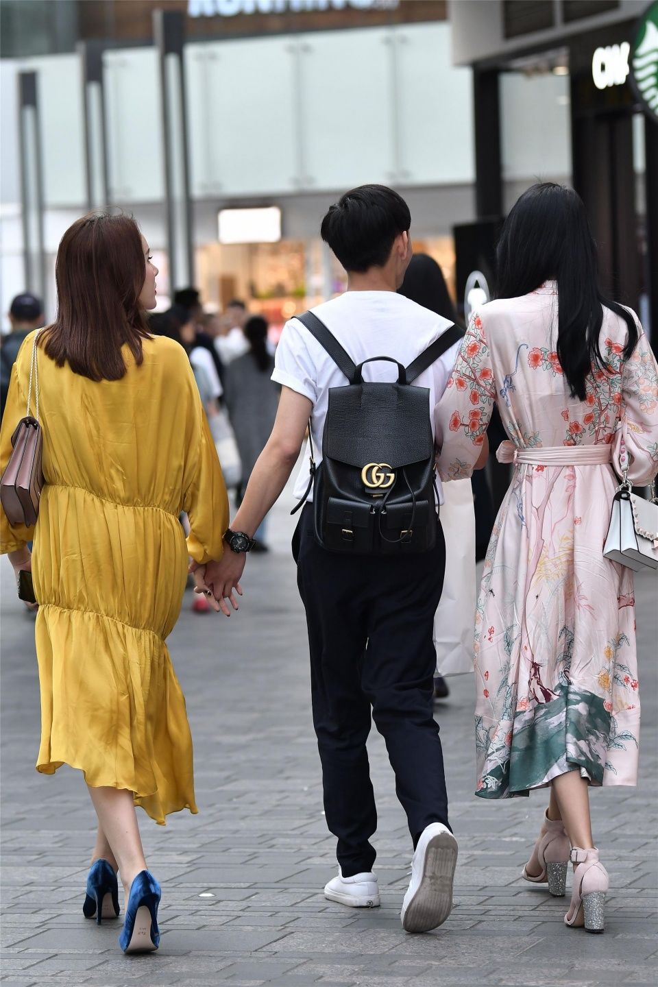 小伙子带着两位时尚长裙的姑娘，哪一位是他的女友呢?