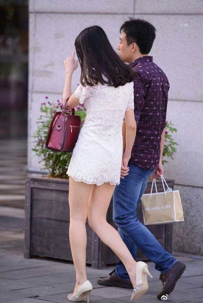 走在街上的小姐姐身穿白色连衣裙,展示出别致的美感