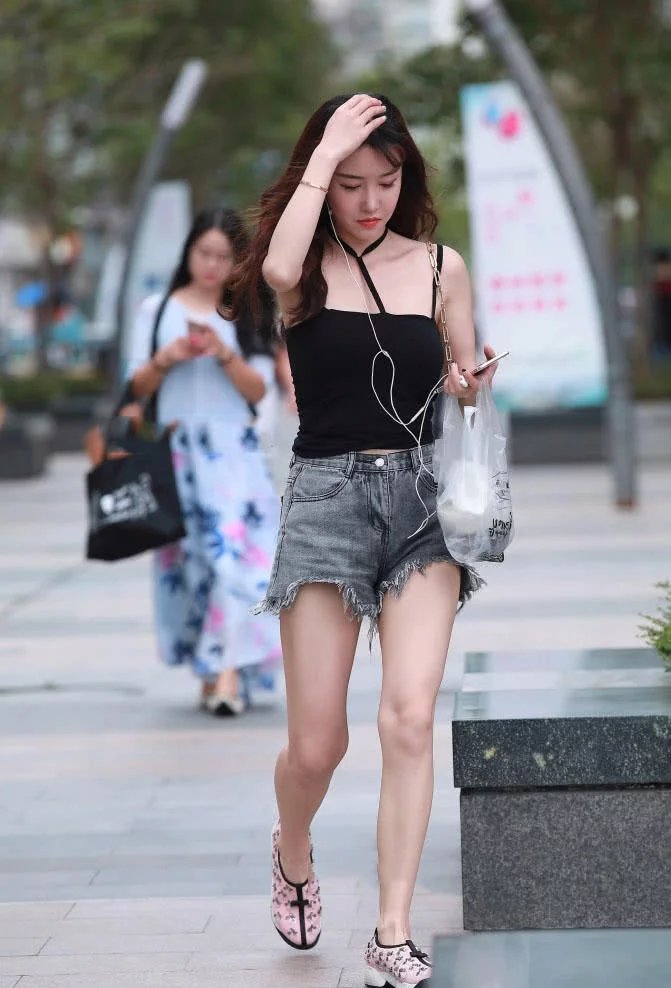 娇美小姐姐吊带背心搭配热裤显出曼妙身材，轻抚头发的样子好迷人