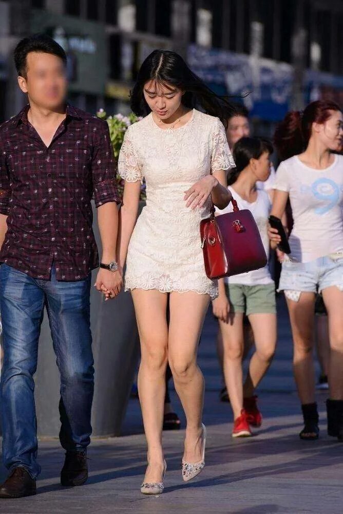 走在街上的小姐姐身穿白色连衣裙，展示出别致的美感