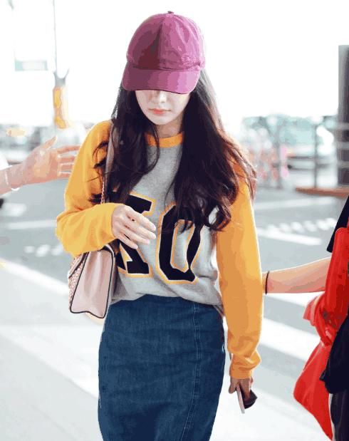 杨幂现身机场打扮时尚，黄色上衣搭配牛仔短裙，低头耳语笑容温暖