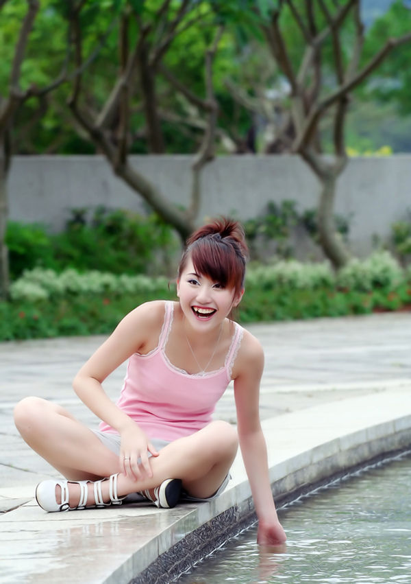 阳光下一个衣着粉色背心的清甜可爱小妹